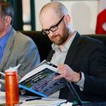 Port Angeles School Board President Joshua Jones reads through the first and last yearbook for the North Olympic Peninsula Skills Center during a school board meeting Thursday. (Jesse Major/Peninsula Daily News)
