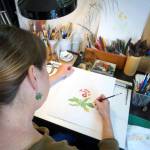 Botanical artist Andrea Woods works on a watercolor painting. Woods&rsquo; works will be on display at Imagine It Framed through September. (Andrea Woods)