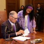 Gov. Jay Inslee reads veto messages while legislative assistant Angie Adams looks on Friday in Olympia. (Rachel La Corte/The Associated Press)