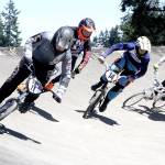 A qualifier for the Washington state BMX championships was held Sunday at the Lincoln Park BMX track. Over 200 riders from ages 3 to 70 entered the various &ldquo;motos&rdquo; to try to earn their way to the state championships in Richland over Labor Day weekend. In this face, from left are Bailey Conners (11) from Puyallup, #14 is Casey Cramer (14) from Des Moines and Preston Stevens (15) of Milton rounding the big curve on the track. (Dave Logan/for Peninsula Daily News)