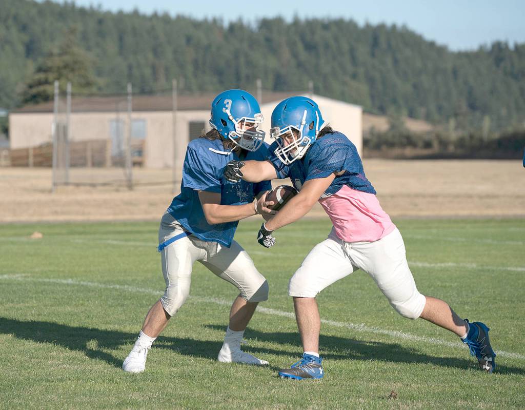 Chimacum quarterback Cole Dotson, hands the ball off to running back Logan Storm during a preseason practice.                                Steve Mullensky/for Peninsula Daily News