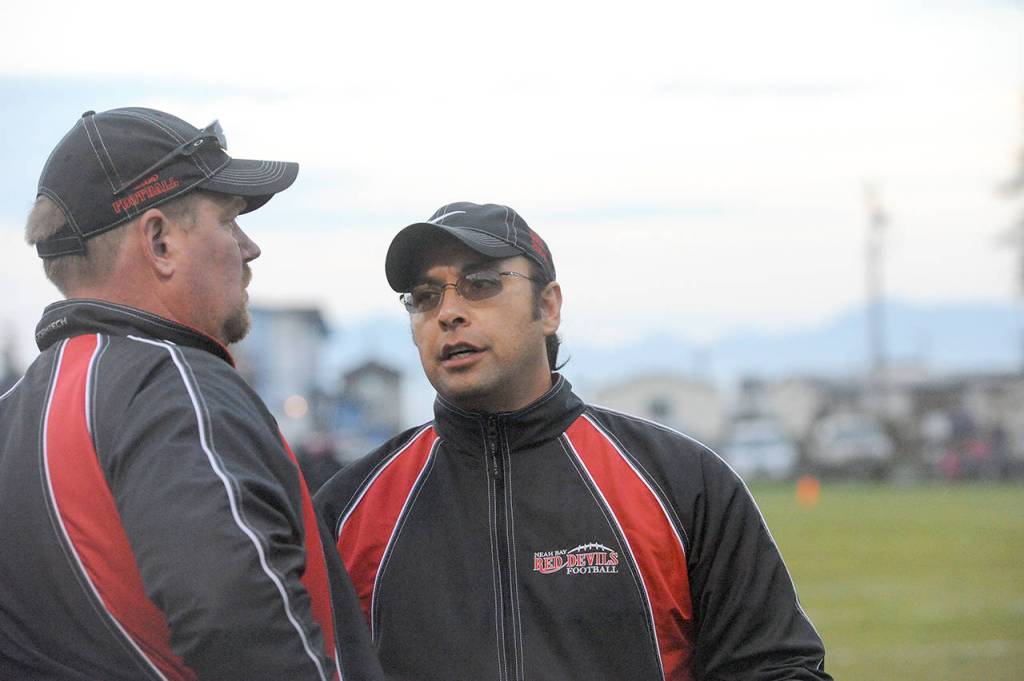 Lonnie Archibald/for Peninsula Daily News                                Neah Bay head coach Tony McCaulley, left, talks with Red Devils defensive coordinator T.J. Greene. McCaulley said the coaching staff is looking forward to the challenge of coaching many new players this season.