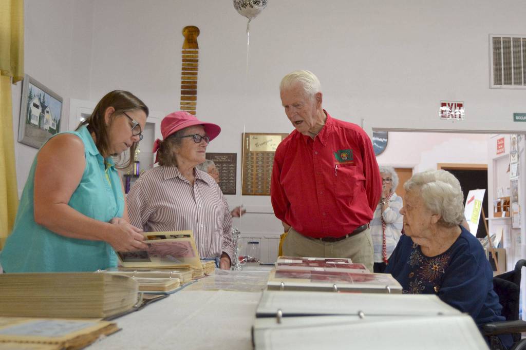 At the 75th anniversary for the Sequim Prairie Grange, from left, Sherry Ritchie, Joan Ritchie, Bob Clark, grange master, and Beanie Ellis look through the grange&rsquo;s scrapbooks and talk about old times on Aug. 9. Sequim Gazette photo by Matthew Nash