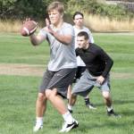 Dave Logan/for Peninsula Daily News Port Angeles quarterback Brenden Roloson-Hines, front, catches the snap while running back Riley Gale awaits a handoff during the first day of high school football practice Wednesday. The Roughriders had 50 players turn out on day one.