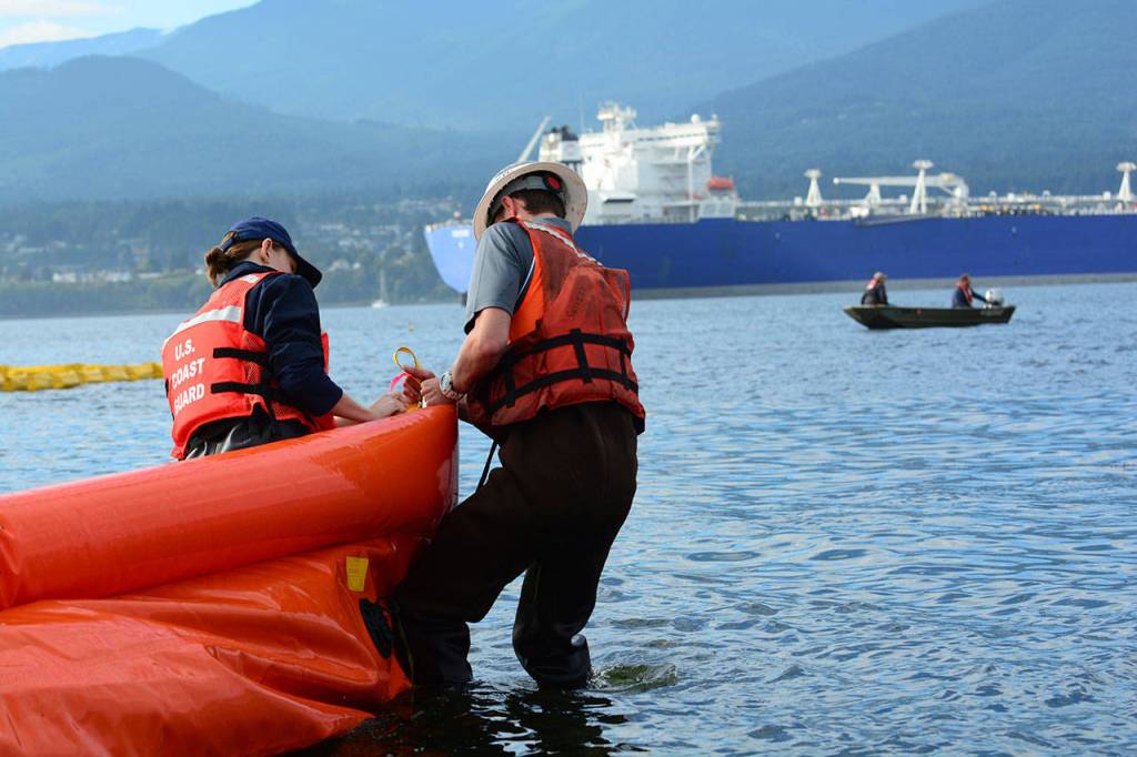 Crews anchor an oil spill boom to the shore of Ediz Hook during training Wednesday. (Jesse Major/Peninsula Daily News)