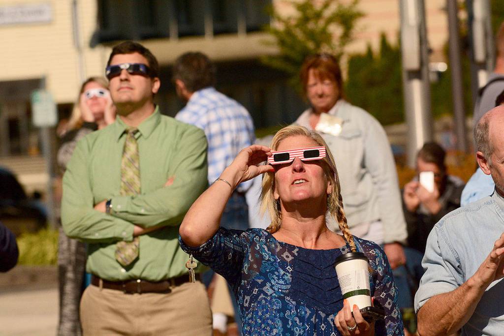 A crowd from the Clallam County Courthouse watches the solar eclipse Monday morning. (Jesse Major/Peninsula Daily News)