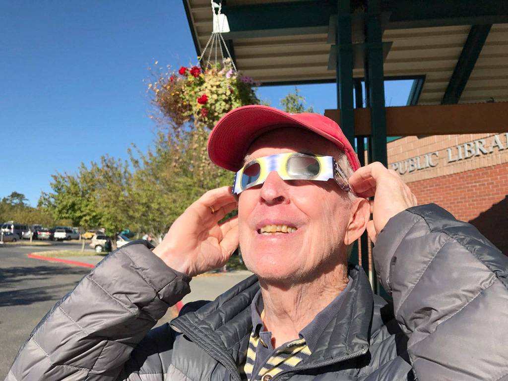 Sequim resident John Magee looked sunward during the beginning of the solar eclipse Monday at the Port Angeles library while wearing safety glasses handed out by library staff. (Paul Gottlieb/Peninsula Daily News)