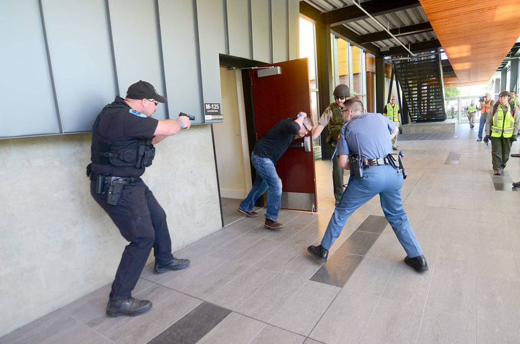 A man portraying a shooting witness barges through a door as officers search for a shooter during an active shooter training at Peninsula College on Thursday. (Jesse Major/Peninsula Daily News)