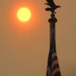 The sun shines behind a flagpole in front of the Clallam County Courthouse in Port Angeles at midmorning Tuesday as layers of smoke from wildfires in Eastern Washington and Montana filter the light to shades of orange and red. (Keith Thorpe/Peninsula Daily News)