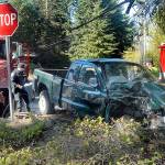 Keith Thorpe/Peninsula Daily News Port Angeles police Officer T.J. Mueller, left, investigates the scene where a pickup truck and a semi-trailer collided at the intersection of 10th and N streets in Port Angeles on Tuesday.