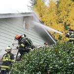 Firefighters spray water at a fire through a window of a residence in the 70 block of Chimacum Creek Road on Monday morning. The fire claimed two pets, a cat and a dog. (East Jefferson Fire & Rescue)