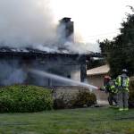 Firefighters with Clallam County Fire District No. 3 hose down the front of a home on Thornton Drive. (Matthew Nash/Olympic Peninsula News Group)