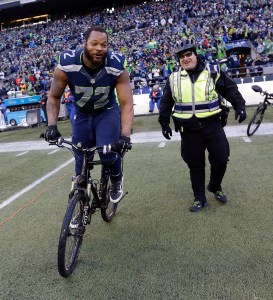 Seattle Seahawks' Michael Bennett borrows a police officer's bike after overtime of the NFL football NFC Championship game against the Green Bay Packers. (The Associated Press)