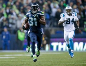 Seattle Seahawks strong safety Kam Chancellor runs in front of Carolina Panthers tight end Ed Dickson to score on an interception 90 yards for a touchdown during the second half Saturday night at CenturyLink Field. (The Associated Press)