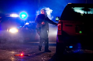 A Oregon State police officer stands by a vehicle as police officers block Highway 395 in Seneca