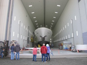 Members of a tour group gaze up at a yacht under repair in a massive Westport Yachts repair bay