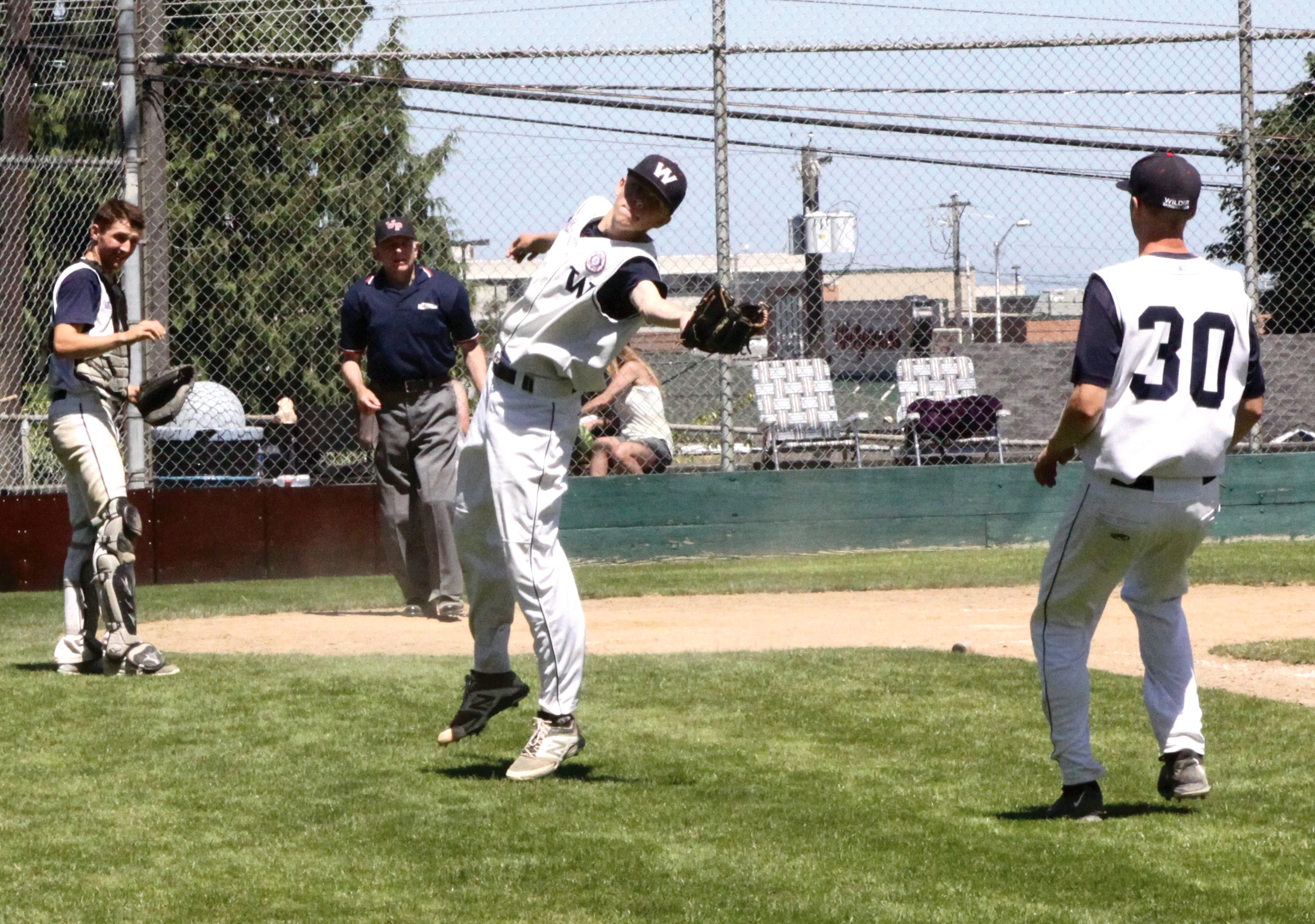 Wilder pitcher Janson Pederson reaches back to catch a foul fly ball as Wilder first baseman Larsson Chapman (30) and catcher Ricky Crawford