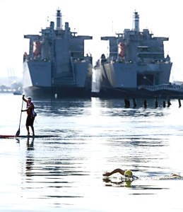 A support team on a stand-up paddleboard monitors Seattle resident Andrew Malinak as he begins an attempt to duplicate a historic 18.8-mile swim from Tacoma to Seattle. (Drew Perine/McClatchy News Service)