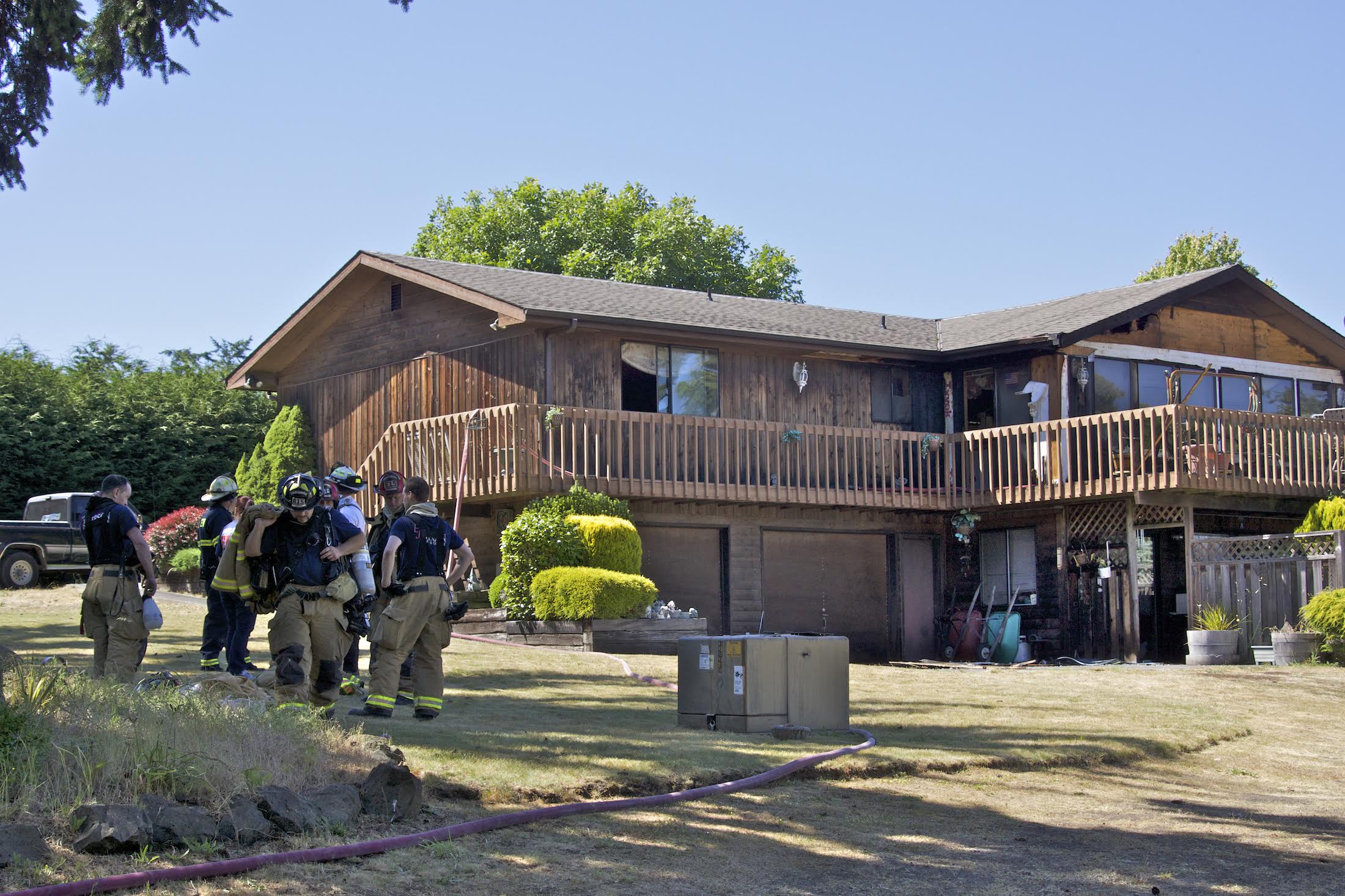 Firefighters confer after dousing a structure fire that occurred in the lower right unit of a house on 27th Street in Port Townsend on Wednesday afternoon. (Steve Mullensky/for Peninsula Daily News)