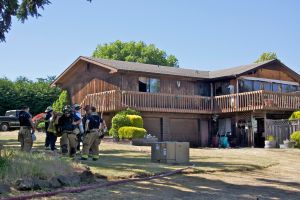 Firefighters confer after dousing a structure fire that occurred in the lower right unit of a house on 27th Street in Port Townsend on Wednesday afternoon. (Steve Mullensky/for Peninsula Daily News)