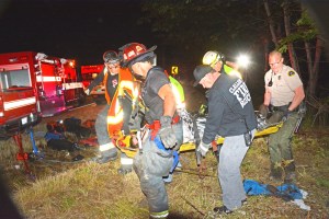 A rescue crew carries an unnamed victim up from the crash site on Black Diamond Road on Friday morning. From left