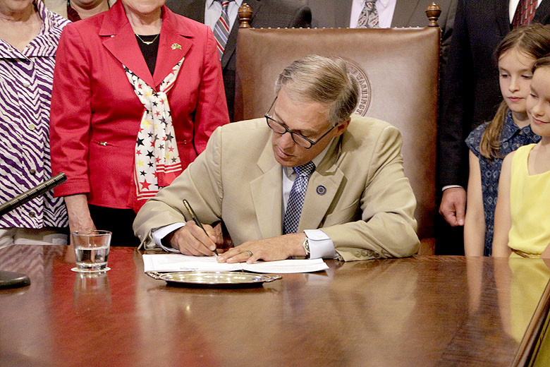 Gov. Jay Inslee signs a bill Monday in Olympia cutting tuition at the state's colleges and universities. National experts on college tuition have called Washington's tuition cut a rare move that could influence other states. The Associated Press