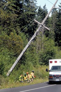 Rescue workers from Clallam County Fire District No. 3 work their way into the bushes along Old Olympic Highway east of Port Angeles to assist the driver of a pickup truck that ran off the road and sheared a power pole on Tuesday. Keith Thorpe/Peninsula Daily News