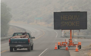 A sign warns of "Heavy Smoke" on Washington state Highway 155 near Omak on Wednesday (Aug. 26). Wildfires in the area have generated heavy smoke that has slowed traffic and in some instances hindered efforts to fight the fires from the air. The Associated Press