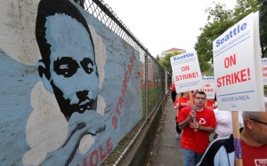 Striking Seattle School District teachers and other educators walk a picket line past an image of Martin Luther King Jr.