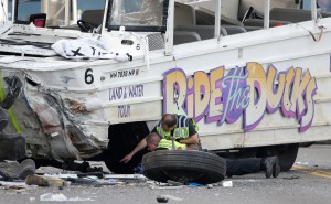 Seattle Police officers look under a "Ride the Ducks" tourist vehicle as a tire and wheel from the bus sits nearby before the bus is loaded onto a flatbed tow truck Thursday following a fatal crash with a charter passenger bus earlier that day in Seattle. The Associated Press