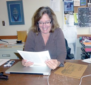 Port Townsend Wooden Boat Festival Director Barb Trailer inspects some of the art that will be used to promote this years event.  Charlie Bermant/Peninsula Daily News ()