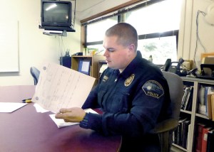 Port Townsend Police Detective Luke Bogues reads a report about a recent mental health-related police action.  Charlie Bermant/Peninsula Daily News ()