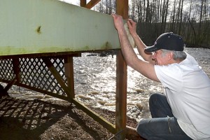 Matt McWilliams looks below his Sequim home's deck that is threatened to be swept away by the Dungeness River. (Matthew Nash/Olympic Peninsula News Group)