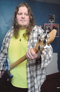 John Kingsley of Port Angeles holds a damaged bass guitar that he said was thrown over a fence by a burglar Friday. —Photo by Keith Thorpe/Peninsula Daily News ()