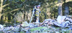 A South Kitsap Fire and Rescue firefighter collects a hose at the site of a home explosion in the 3800 block of Soholt Lane in Port Orchard on Tuesday. The remains of two people were found following a powerful explosion that morning that leveled a home in Western Washington.  Larry Steagall/Kitsap Sun via AP ()