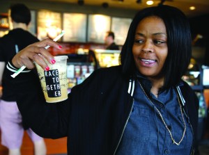 Larenda Myres holds an iced coffee drink with a Race Together sticker on it at a Starbucks in Seattle on Wednesday.  The Associated Press ()