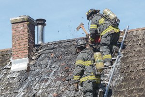 Clallam County Fire District No. 2 firefighters crawl onto a smoldering roof at 73 Gakin Road west of Port Angeles on Tuesday.  Jay Cline/Clallam County Fire District No. 2 ()