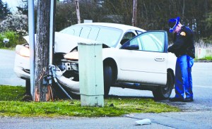 A State Trooper fills out paperwork as he examines a 2001 Ford Taurus that struck a power pole near the intersection of Mount Pleasant Road and U.S. Highway 101 on Sunday at about 7:38 p.m. The wreck cut off power to residents in the Deer Park area until noon Monday.  Jay Cline/Clallam County Fire District No. 2 ()
