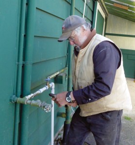Jefferson County Fairgrounds Manager Bill McIntire repairs a water pipe Monday. McIntire said he wont stop members of a tent city from camping at the fairgrounds but will not relax the 10-day limit.  Photo by Charlie Bermant/Peninsula Daily News ()