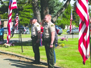 Clallam County Sheriff's Deputies Mike Bakes and Paul Federline salute during the 2015 Memorial Day ceremony at Mount Angeles Memorial Park in Port Angeles. Bakes is a Vietnam-era U.S. Marine Corps veteran