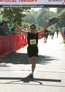 Marathon winner Yusheng Ni puts two thumbs in the air as he crosses the finish line. (Dave Logan/for Peninsula Daily News)