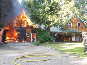 A garage is engulfed in flames Monday at a property in Coyle. (Denise Karp/Quilcene Fire Rescue)