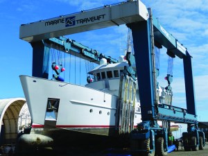 The Surfbird is suspended in a borrowed TraveLift at Platypus Marine in Port Angeles Harbor.  David G. Sellars/for Peninsula Daily News ()