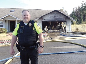 Port Townsend Police Officer Garen Williams stands in front of the home after carrying one of the occupants to safety. Crystal Craig/East Jefferson Fire-Rescue