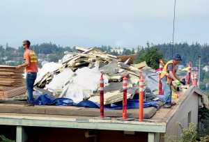 Workers gather debris from the roof at Mountain View Commons during its replacement process