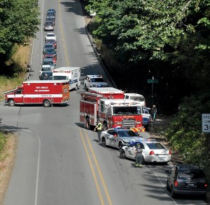 Emergency vehicles gather at the spot where a pickup truck left U.S. Highway 101 at high speed and tumbled into a ravine at Valley Creek near Pine Street in Port Angeles on Wednesday. (Keith Thorpe/Peninsula Daily News)