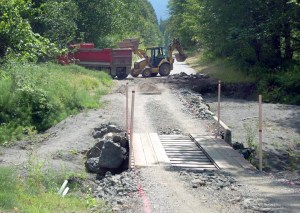 An excavator loads pieces of old roadway into a dump truck last week at the site of a washout on Olympic Hot Springs Road in the Elwha Valley of Olympic National Park. The road was heavily damaged by floods last winter. Two campgrounds in the valley remain closed due to flood damage.  Keith Thorpe/Peninsula Daily News ()