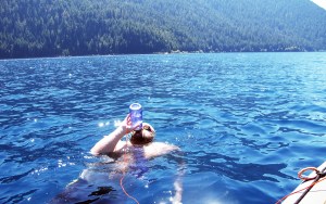 Erik Spellman pauses to drink water during his swim of the length of Lake Crescent earlier this month. This photo was taken by girlfriend Megan Hart from a kayak Hart paddled to follow the swimmer from East Beach to Fairholme.