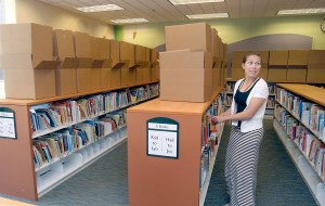 Childrens librarian Jennifer LuBecke straightens a shelf while boxes wait to be filled with books at the Port Angeles Public Library on Friday.  Keith Thorpe/Peninsula Daily News