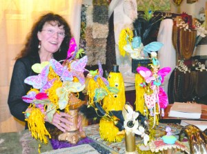 Jeanne Moore arranges some of the trophies to be awarded to entries in the Grandly Local Parade during Saturday's Uptown Street Fair in Port Townsend. Charlie Bermant/Peninsula Daily News